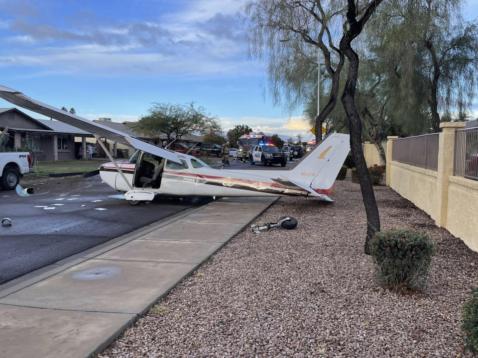 This photo provided by Goodyear Police Department shows a plane after an emergency crash landing on a neighborhood street in Goodyear, Ariz., Saturday, Feb. 10, 2024. The single engine plane experienced mechanical problems shortly after takeoff from nearby Glendale Airport, police said. The pilot and lone passenger escaped injury. (Goodyear Police Department via AP)