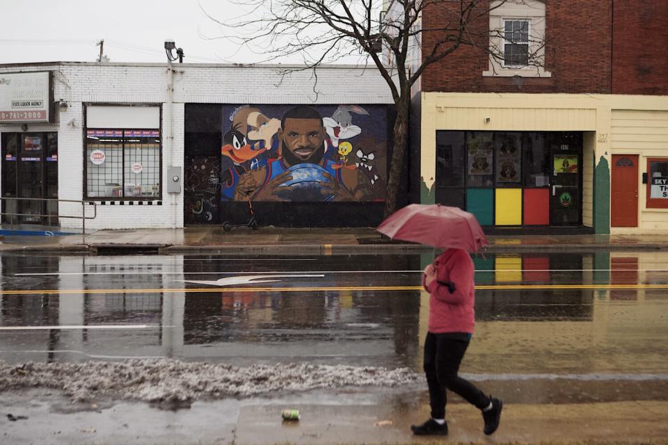 A person with an umbrella walks past the LeBron James "Space Jam" mural.