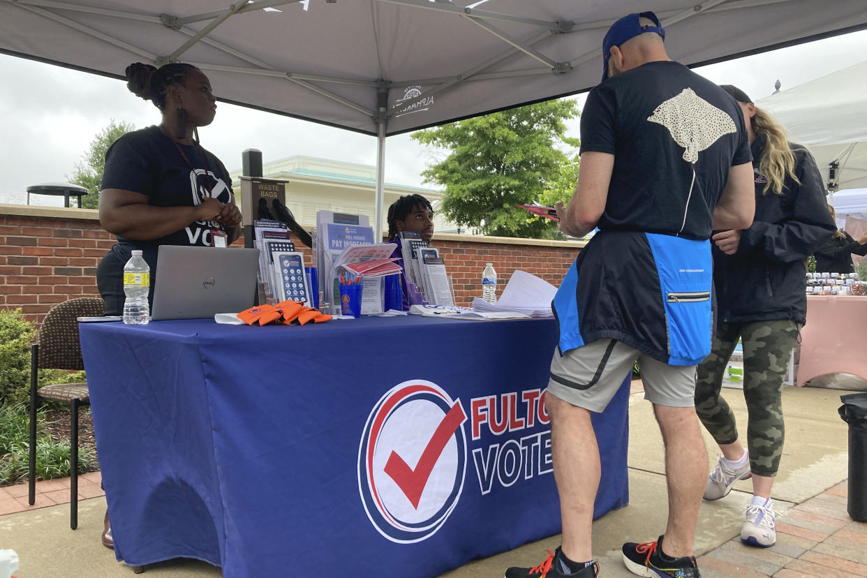 People visit a booth set up by Fulton County to recruit new poll workers at the Alpharetta Farmers Market on Sept. 10, 2022, in Alpharetta, Ga. (Sudhin Thanawala/AP)