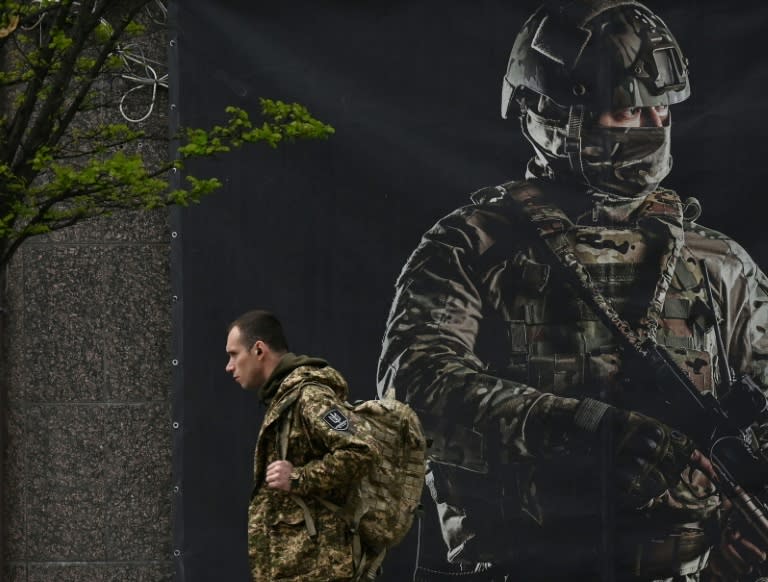 Un soldado ucraniano pasa junto a un cartel de reclutamiento en Kiev el 23 de abril de 2024. (Sergei SUPINSKY)