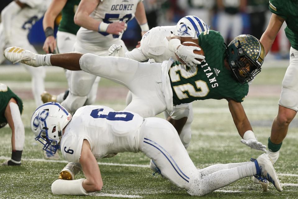 Blessed Trinity's Justice Haynes (22) is sent flying by Oconee County's Liam Lewis (6) during the GHSA high school football AAAA state championship game between Blessed Trinity and Oconee County on Saturday, Dec. 14, 2019, in Atlanta.