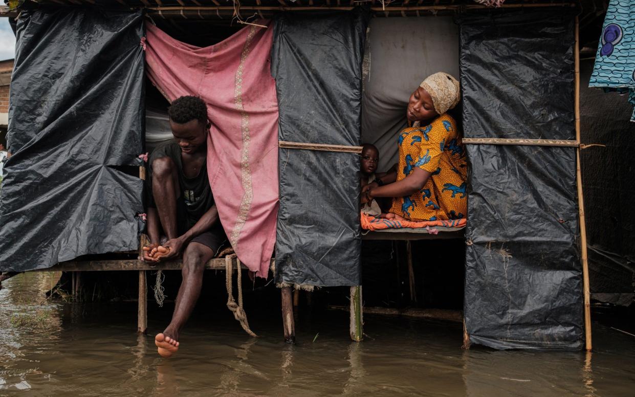 Uwurukundo Zilfa (R) sits next to her husband and kid inside their temporary shelter after being displaced following flash floods in the Gatumba district of Bujumbura