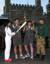 LONDON, ENGLAND - JULY 20: Dame Kelly Holmes lights her torch as Marine Martyn Williams holds the flame during the London 2012 Olympic Torch Relay on July 20, 2012 in London, England. The Olympic Flame is now on day 63 of a 70-day relay involving 8,000 torchbearers covering 8,000 miles. (Photo by Jan Kruger/Getty Images)