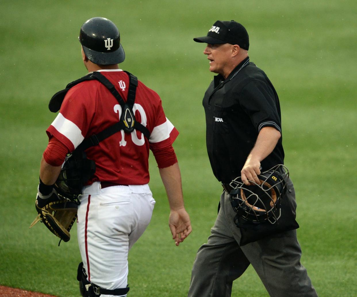 The home plate umpire asks Indiana catcher Kyle Schwarber (10) to get back home after he slapped first base disputing the call during the Stanford Indiana NCAA Baseball Regional at Bart Kaufman Field in Bloomington, Ind. Sunday, June 1, 2014.