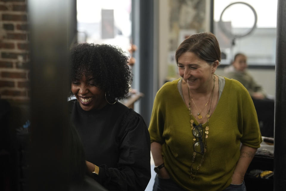 Hairdresser, Aude Livoreil-Djampou, right, laughs with one of the staff in her hairdressing salon, in Paris, Wednesday, March 27, 2024. French lawmakers are debating a bill Thursday that would ban discrimination over the texture, length, color or style of someone's hair. (AP Photo/Thibault Camus)