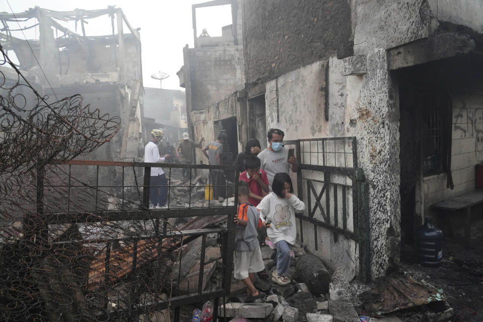 Residents walk though the rubble at a neighborhood affected by a fuel depot fire in Jakarta, Indonesia, Saturday, March 4, 2023. A large fire broke out at the fuel storage depot in Indonesia's capital Friday, killing multiple people, injuring dozens of others and forcing the evacuation of thousands of nearby residents after spreading to their neighborhood, officials said. (AP Photo/Tatan Syuflana)