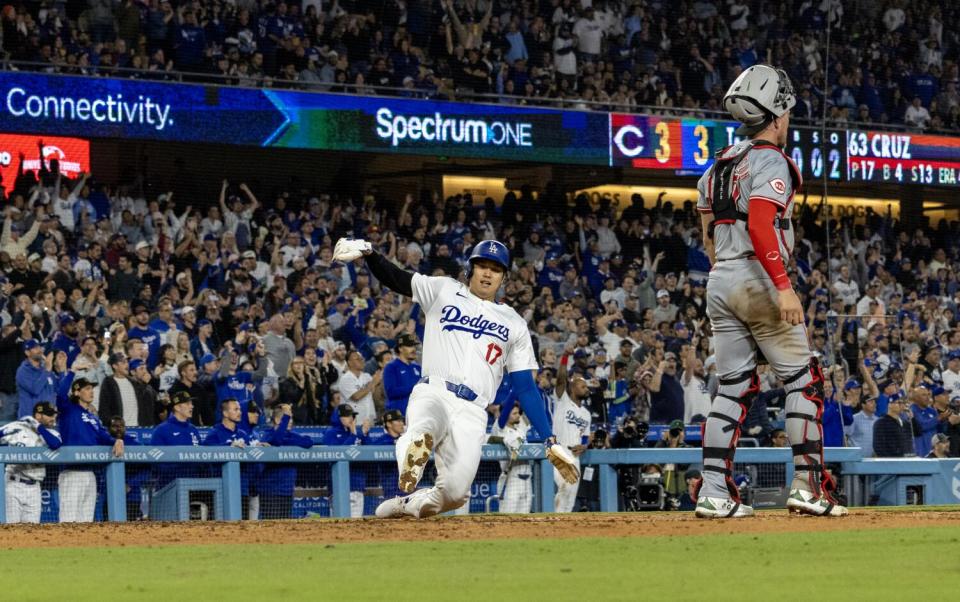 Dodgers 'designed hitter' Shohei Ohtani glijdt veilig de thuishaven binnen en scoort vrijdagavond het leidende punt tegen de Reds.