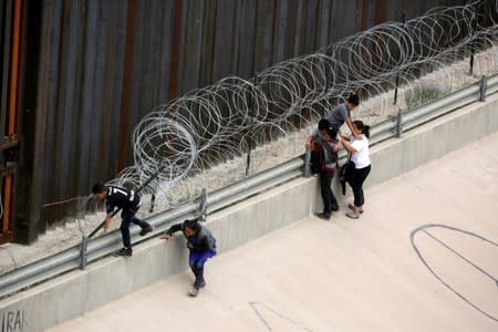 Migrants walk along the border fence after crossing illegally into El Paso, Texas, U.S. as seen from Ciudad Juarez