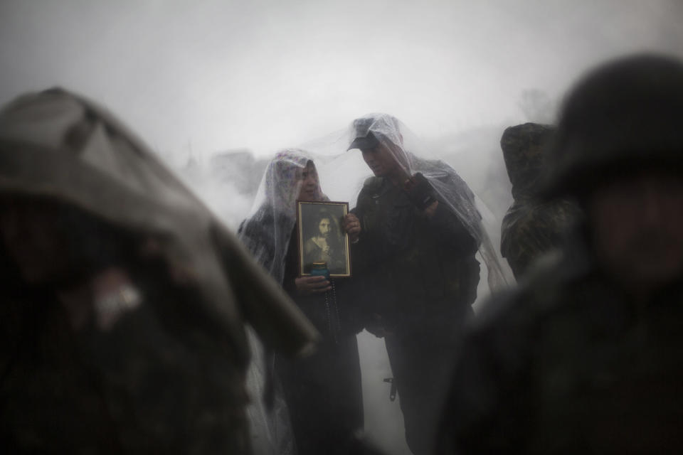 A Pro Russian woman and an Ukrainian Army commander take cover from the rain while Pro Russia civilians block the road in the village of Andreevka, 10 km south of Slavyansk , Ukraine, Friday, May 2, 2014. Russia has massed tens of thousands of troops in areas near Ukraine’s border. Kiev officials claim Russia is preparing to invade and that it is fomenting the unrest in the east, where insurgents have seized government buildings in about a dozen cities in towns. Moscow denies the allegations, but Foreign Minister Sergey Lavrov has warned Russia would respond to attacks on Russian citizens or interests in the east. (AP Photo/Manu Brabo)