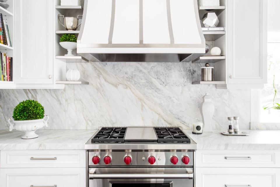 A marble backsplash anchors a white kitchen. 