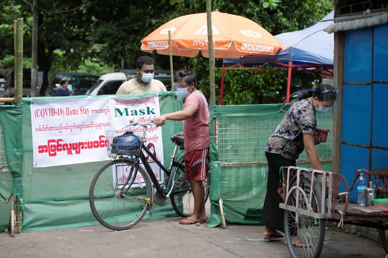 People walk past a makeshift barricade blocking off a street to prevent the spread of the coronavirus disease in Yangon