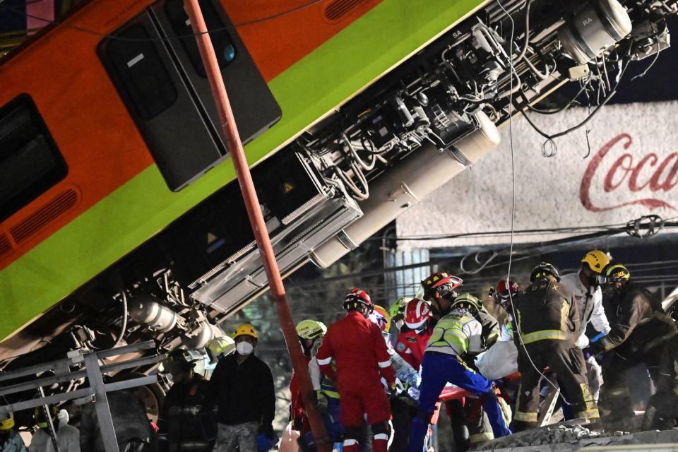 Rescue workers remove a body from a train carriage near a fallen Metro car.