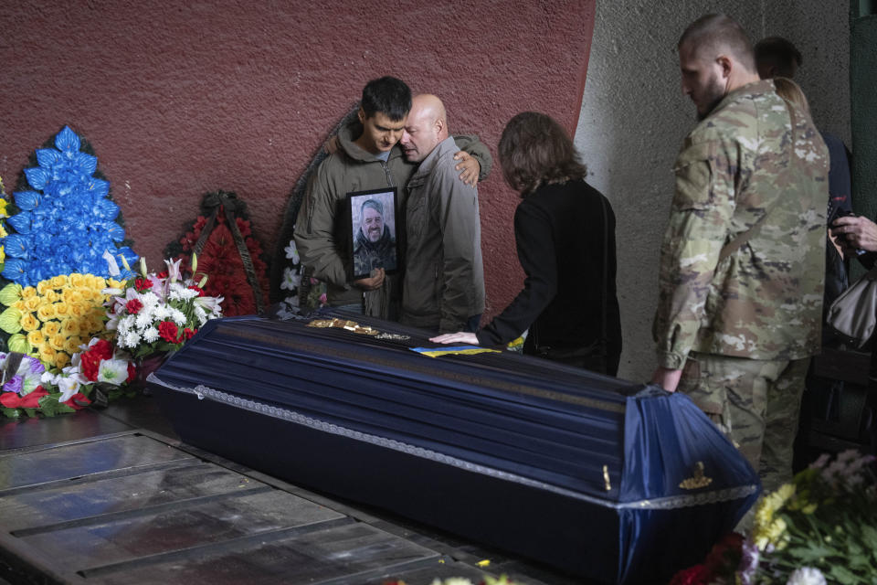 People pay last respect by the coffin of US citizen Volodymyr Myroniuk, known by the call sign John, 59, a photographer from Los Angeles, who was killed as he was covering a battle with the Russian troops, during a farewell ceremony in Kyiv, Ukraine, Sunday, Oct. 1, 2023. (AP Photo/Efrem Lukatsky)