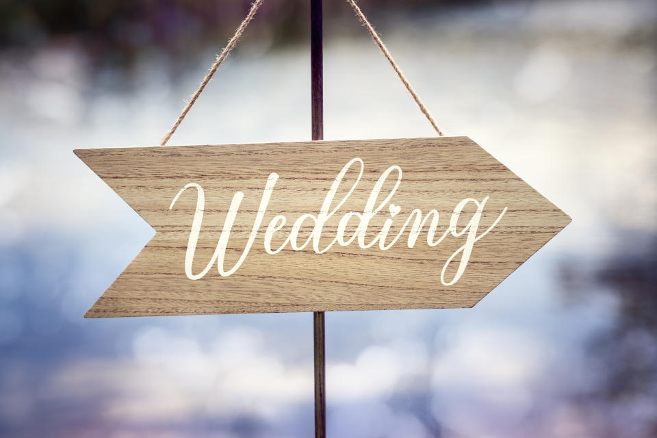 Wedding ceremony wooden arrow location sign with lake reflection background