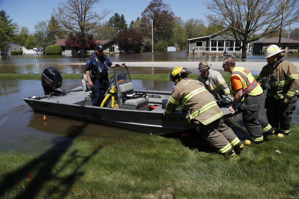 Firefighters launch a boat as the Tittabawassee River overflows, Wednesday, May 20, 2020, in Midland, Mich. People living along two mid-Michigan lakes and parts of a river have been evacuated following several days of heavy rain that produced flooding and put pressure on dams in the area. (AP Photo/Carlos Osorio)