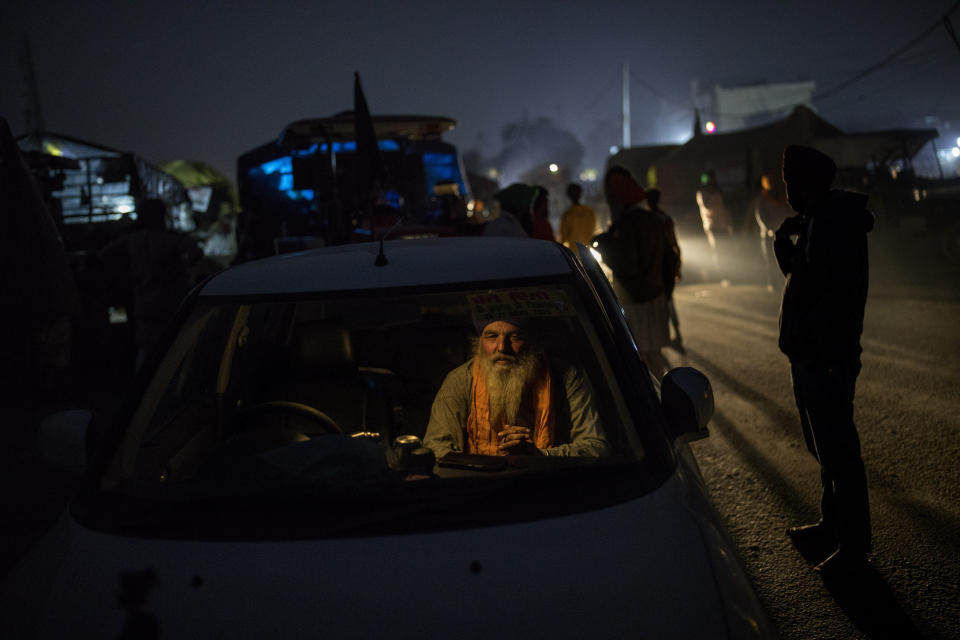 Farmer Bhupinder Singh, 50, sits inside his car parked on a highway as a sign of protest against new farm laws, at the Delhi-Haryana state border, India, Wednesday, Dec. 2, 2020. The convoy of trucks, trailers and tractors stretches for at least three kilometers (1.8 miles). It’s a siege of sorts and the mood among the protesting farmers is boisterous. Their rallying call is “Inquilab Zindabad” (“Long live the revolution”). (AP Photo/Altaf Qadri)