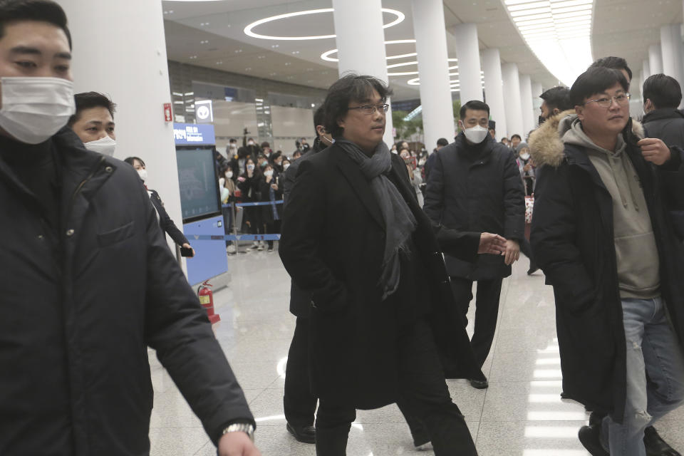 South Korean director Bong Joon-ho, center, arrives at the Incheon International Airport in Incheon, South Korea, Sunday, Feb. 16, 2020. South Koreans are reveling in writer-director Bong's dark comic thriller, "Parasite," which won this year's Academy Awards for best film and best international feature. The movie itself, however, doesn't put the country in a particularly positive light. (AP Photo/Ahn Young-joon)