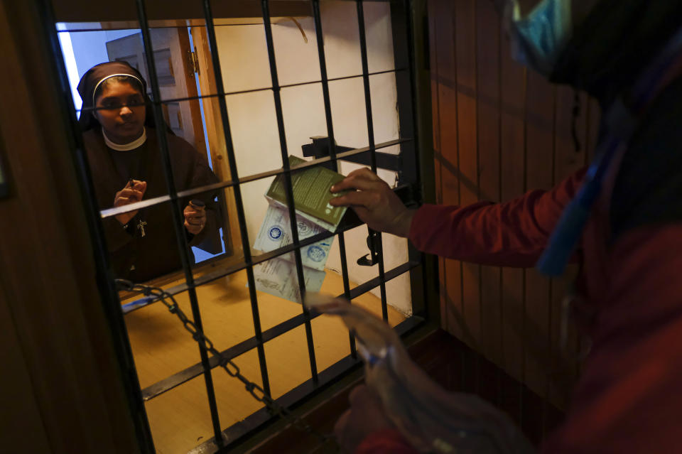 A nun places a stamp at the Saint James Way pilgrim's credential of Alejandro Perez, 31, in Najera, northern Spain, Thursday, April1 5, 2021. The pilgrims are trickling back to Spain's St. James Way after a year of being kept off the trail due to the pandemic. Many have committed to putting their lives on hold for days or weeks to walk to the medieval cathedral in Santiago de Compostela in hopes of healing wounds caused by the coronavirus. (AP Photo/Alvaro Barrientos)