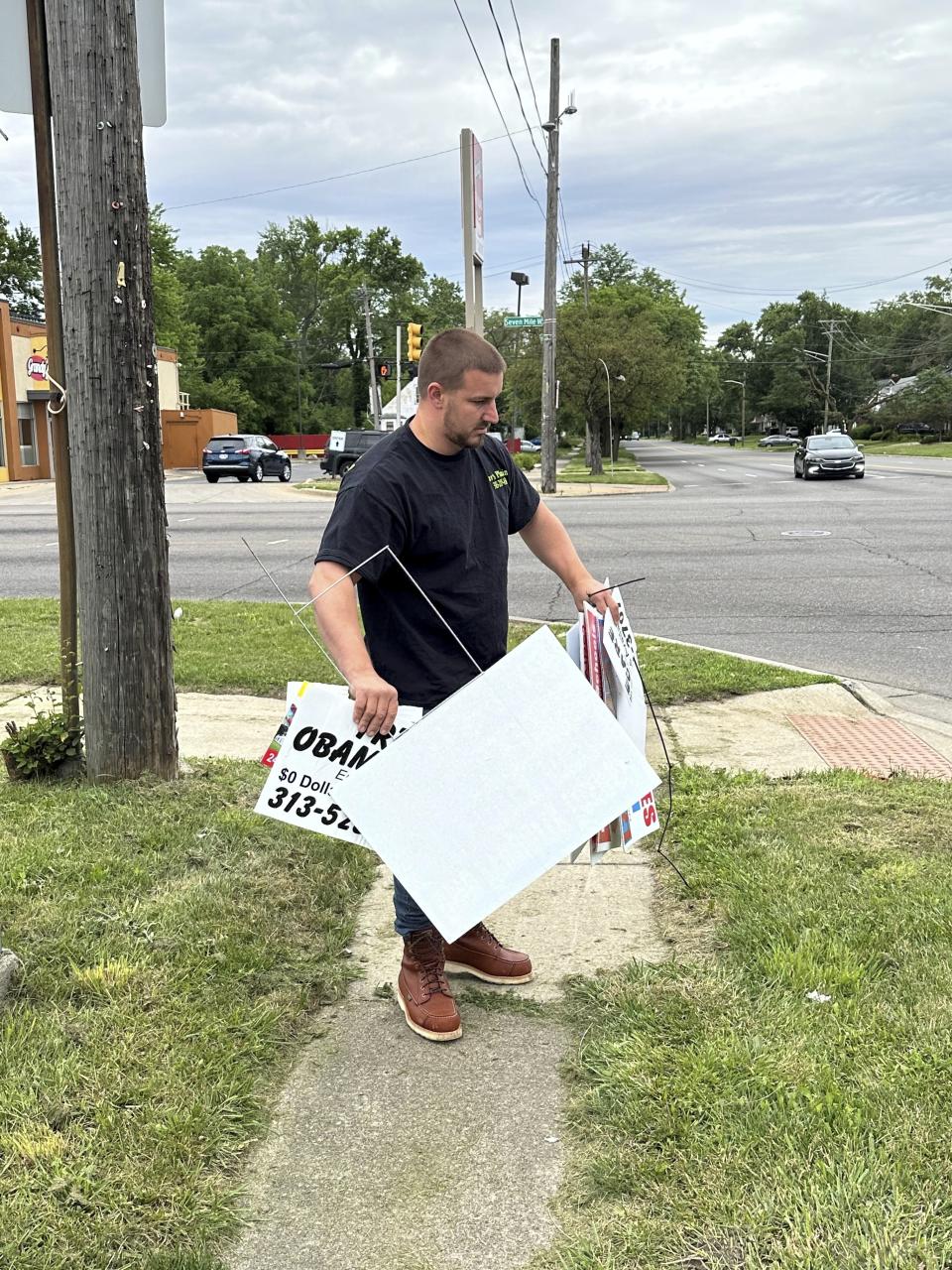 Suburban business owner William Shaw removes illegally posted signs Friday, June 28, 2024, in Detroit, from a street corner in as part of court-ordered community service. The city said that from February 2022 to July 2023, it removed more than 615 "Shaw's Plumbing" signs and he now is under court-order is serving community service removing illegally posted signs in the area. (AP Photo/Corey Williams)