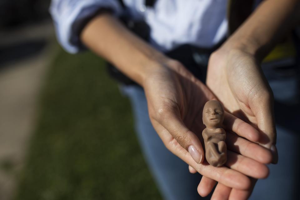 Lexie Hall holds a model of a fetus outside of Planned Parenthood in Columbus. Hall said she has been an anti-abortion activist since she was 16 and started sidewalk counseling in her hometown of Houston with her mother.