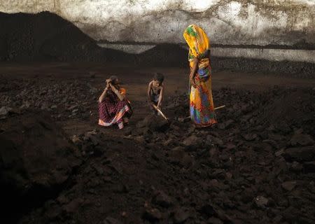 Labourers rest as a boy playfully shovels coal at a yard in the western Indian city of Ahmedabad November 20, 2014. REUTERS/Amit Dave/Files