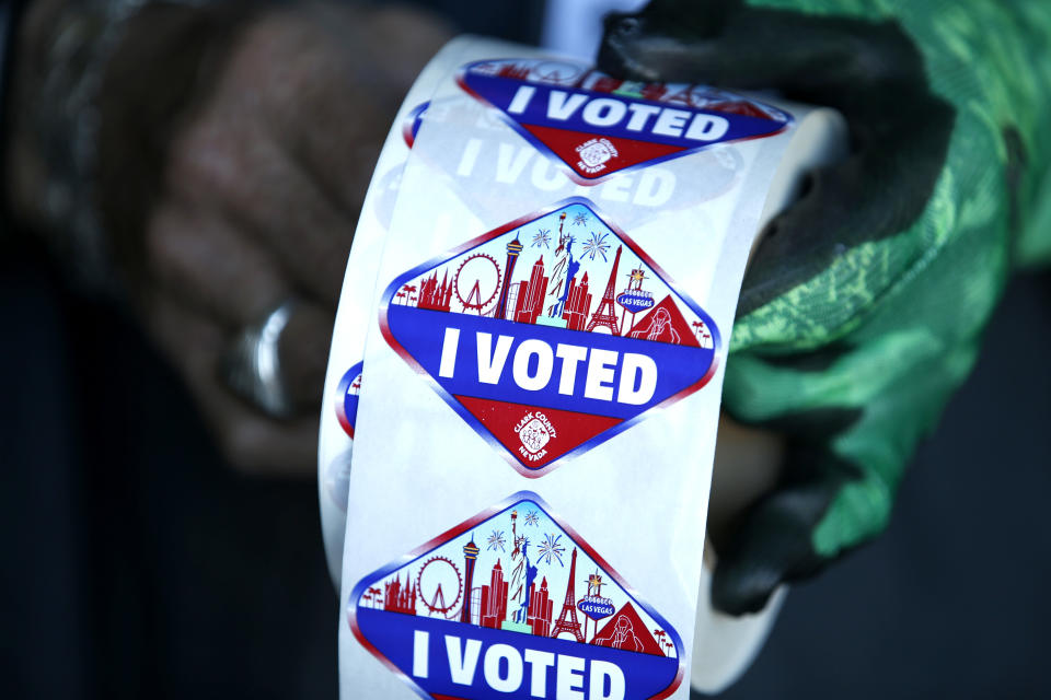 FILE - In this Saturday, Oct. 17, 2020, file photo a poll worker displays "I Voted" stickers during the first day of early voting in Las Vegas. Democrats have kept Nevada in their column in every presidential election since 2004. But political strategists and organizers on the ground warn Nevada is still a swing state. (Steve Marcus/Las Vegas Sun via AP, File)