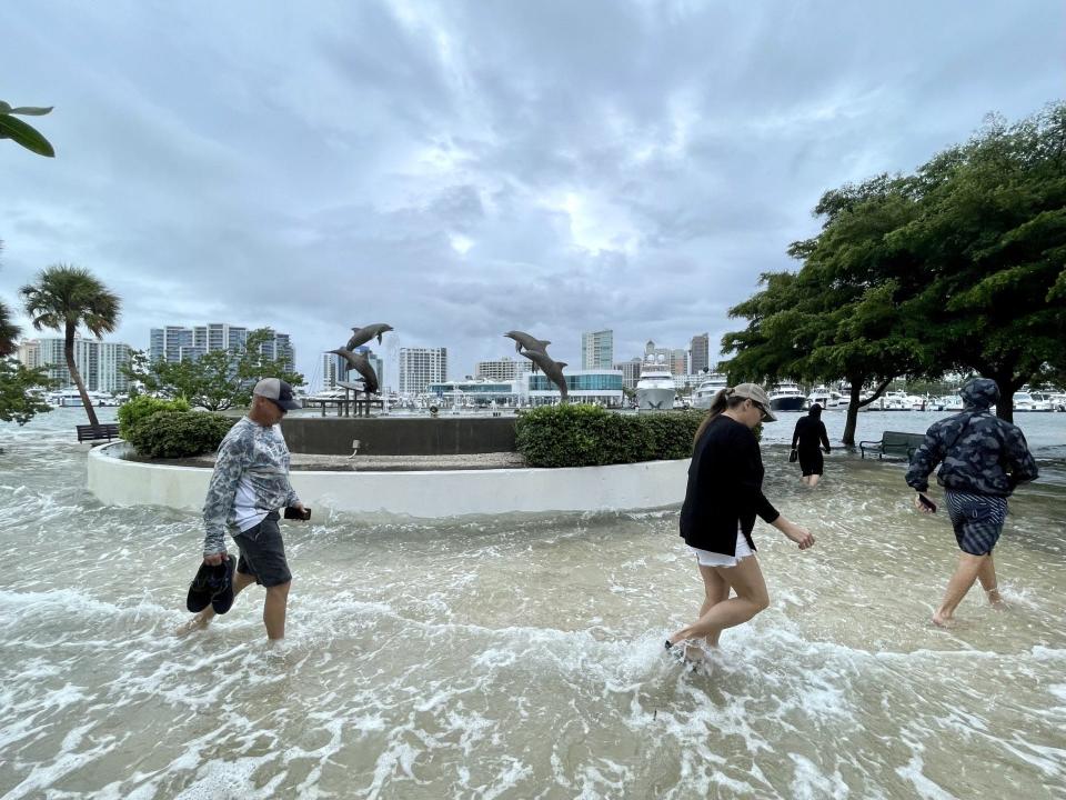 People wade in the floodwaters from Hurricane Idalia last Wednesday at the Dolphin Fountain on the Sarasota Bayfront.