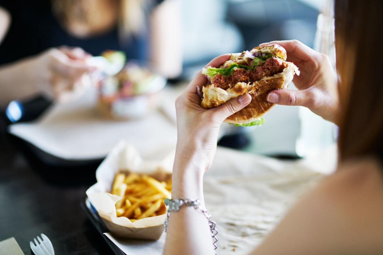 woman eating eating vegan meatless burger in restaurant during the day