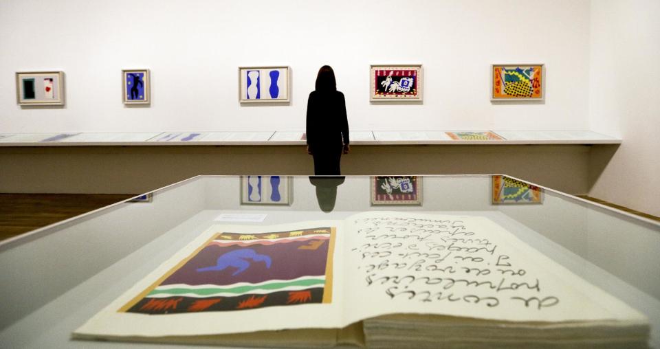 A woman is reflected in a glass cabinet as she looks at artworks by Henri Matisse, on display during a media opportunity at The Tate Modern in London, Monday, April 14, 2014. The artworks are part of the 'Henri Matisse: The Cut-Outs' exhibition that runs at the gallery from April 17 until Sept. 7, 2014. (AP Photo/Kirsty Wigglesworth)