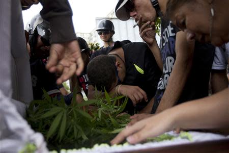 Relatives of a gunshot victim cry over his coffin and smoke marijuana, after forcing the hearse to detour to their neighborhood as a tribute prior to the victim's burial in Caracas November 29, 2012. REUTERS/Carlos Garcia Rawlins