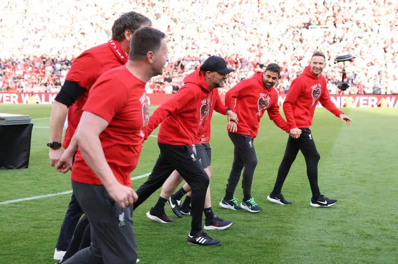 Jürgen Klopp and his Liverpool coaching staff link hands in front of The Kop.