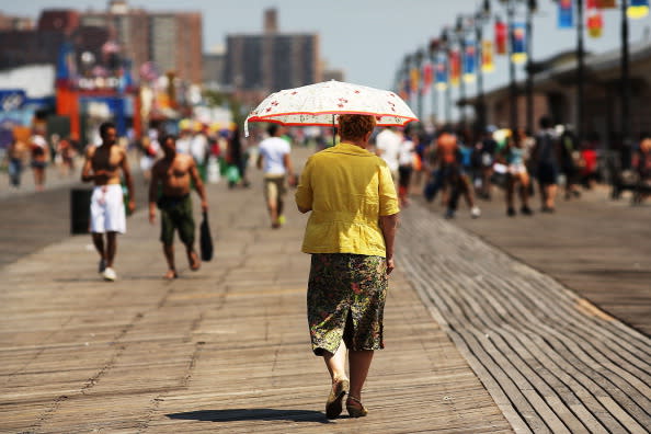 A woman walks down the boardwalk in Coney Island on July 12, 2012 in the Brooklyn borough of New York City. Coney Island has until recently been viewed as a seedy and dilapidating seaside park, however, it is going through a gradual transition which many compare to the renovation of Times Square. In order to accommodate more shops and residential buildings, the Michael Bloomberg administration rezoned Coney Island in 2009. The city also bought seven acres of prime Coney Island real estate promising approximately $150 million in infrastructure upgrades in the area. A recent study found that Coney Island's Luna Park had 640,000 visitors in 2011, the most since Steeplechase Park closed in 1964. (Photo by Spencer Platt/Getty Images)