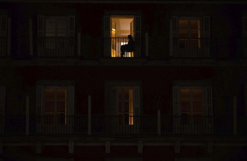 A woman sits on the balcony of her home on the Mayor square in downtown Madrid, Spain, Friday, Oct. 23, 2020. In much of Europe, city squares and streets, be they wide, elegant boulevards like in Paris or cobblestoned alleys in Rome, serve as animated evening extensions of drawing rooms and living rooms. As Coronavirus restrictions once again put limitations on how we live and socialize, AP photographers across Europe delivered a snapshot of how Friday evening, the gateway to the weekend, looks and feels. (AP Photo/Manu Fernandez)