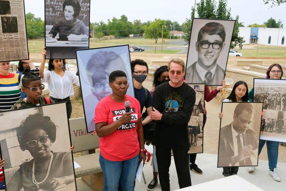 Northeast High School Class of 1970 alumni Brenda Loggins and Rick Gibbens speak at the unveiling of a Legacy Plaza monument celebrating the school, which now houses Classen High School of Advanced Studies at Northeast. Classen SAS students hold photos of Loggins, Gibbens and other Northeast students and teachers from 1960s and 1970s.