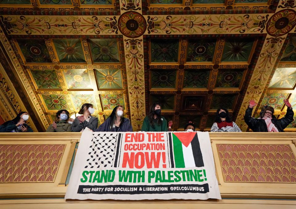 People sitting in the gallery unfurl a banner during a Columbus City Council meeting on Nov. 13, 2023, where hundreds turned out to demand that councilmembers call for a cease-fire in Palestine.