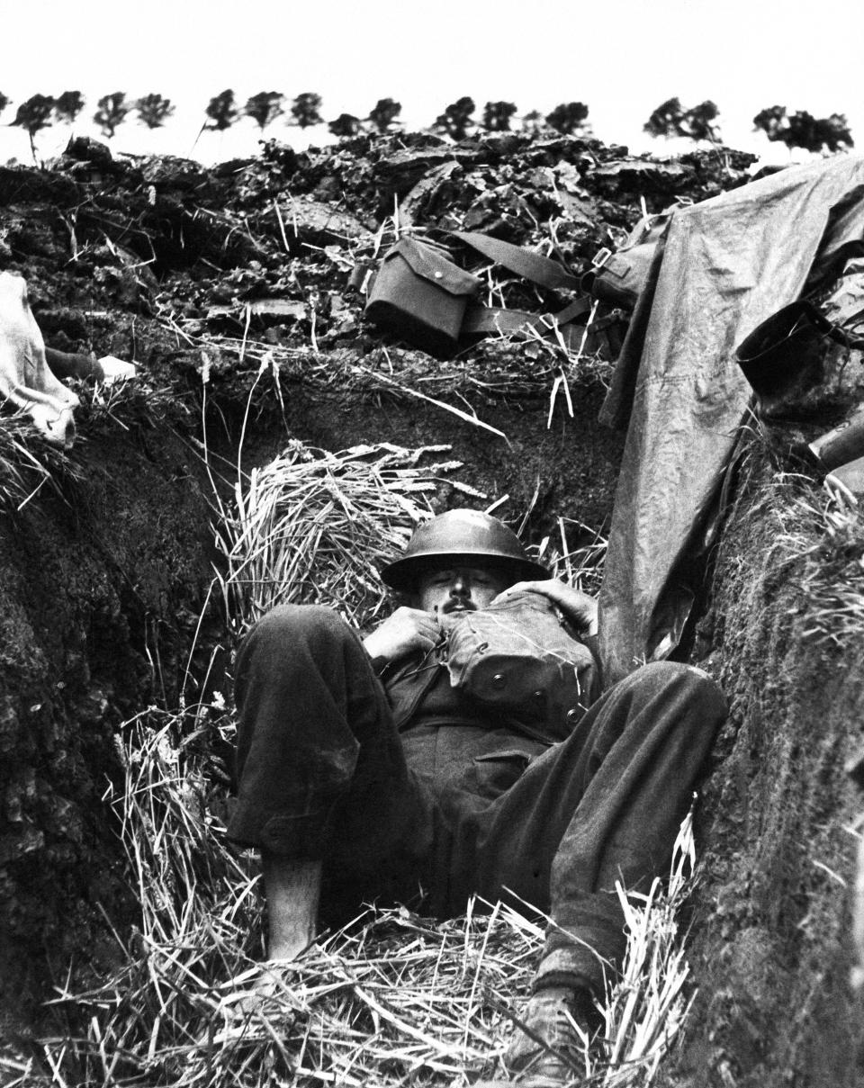 A British soldier napping in rear guard action covering the withdrawal of BEF troops at Dunkirk, France on June 13, 1940. One shoe has been removed by the soldier who piled into the bottom of a hastily constructed trench.