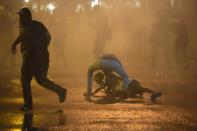 A protester falls as another runs for cover as police fire tear gas shells during a protest near the president's official residence in Colombo, Sri Lanka, Saturday, May 28, 2022. Police fired tear gas and water canon on protesters who marched toward the president Gotabaya Rajapaksa's barricaded residence demanding his resignation. (AP Photo/Eranga Jayawardena)