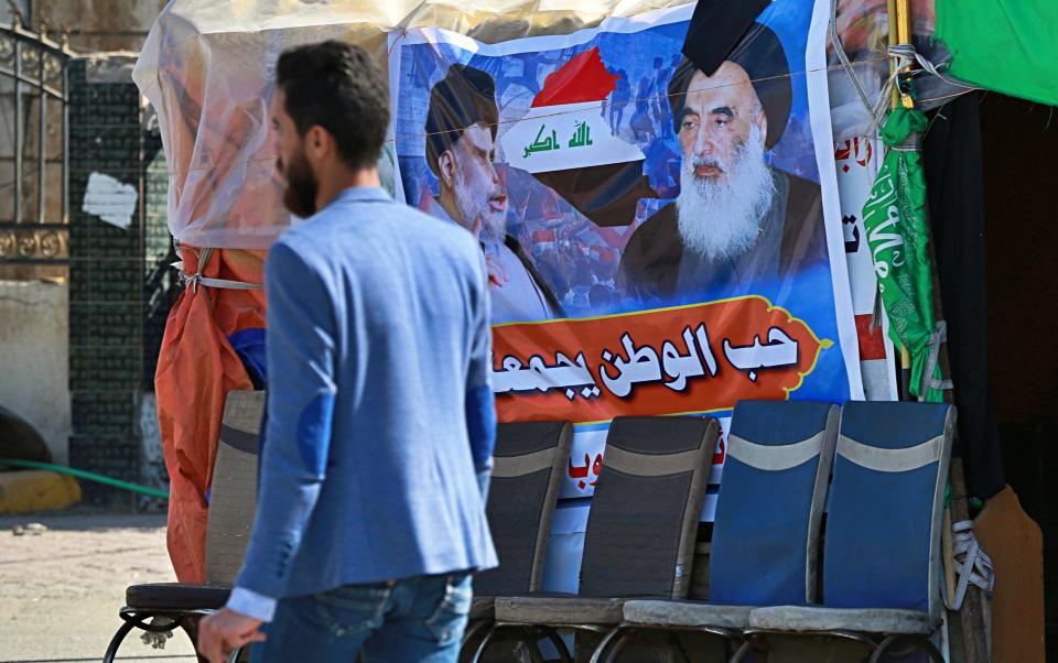 In this Sunday, Feb. 2, 2020 photo, a poster of Shiite spiritual leader Grand Ayatollah Ali al-Sistani, right, and Arabic that reads, "the love of the country bonds us together," is hung in a site of protests, in Najaf, Iraq. Grand Ayatollah Ali al-Sistani, Iraq’s top Shiite cleric, turns 90 this year, and when he recently had surgery it sent chills around the country and beyond. What happens when al-Sistani is gone? Iran is likely to try to exploit the void to gain followers among Iraq’s Shiites. Standing in its way is the Hawza, the centuries-old institution of religious learning which al-Sistani heads and which follows its own tradition-bound rules. (AP Photo/Hadi Mizban)