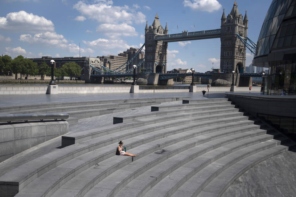 A woman sits in 'More London', during what would normally be the busy lunch period, amid the coronavirus outbreak, in London, Thursday May 21, 2020. (Victoria Jones/PA via AP)