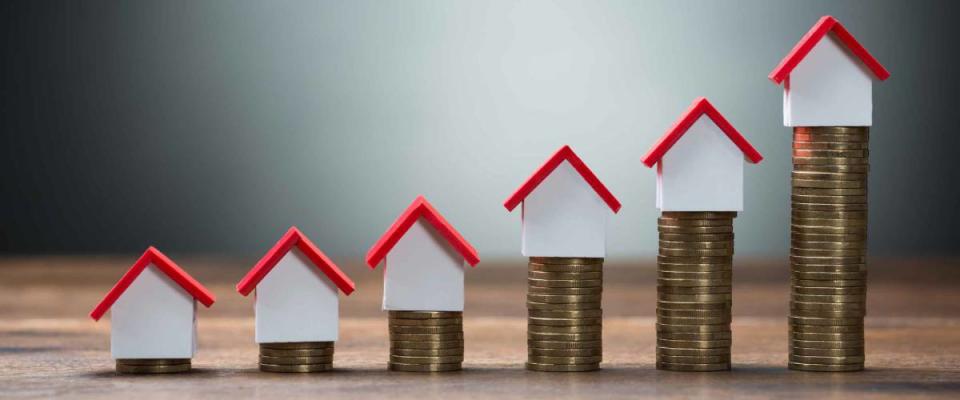 House models arranged on stacked coins at table against gray background