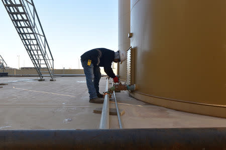 Carlos Riojas adjusts a valve on a storage tank at a wastewater injection facility operated by On Point Energy in Big Spring, Texas U.S. February 12, 2019. Picture taken February 12, 2019. REUTERS/Nick Oxford