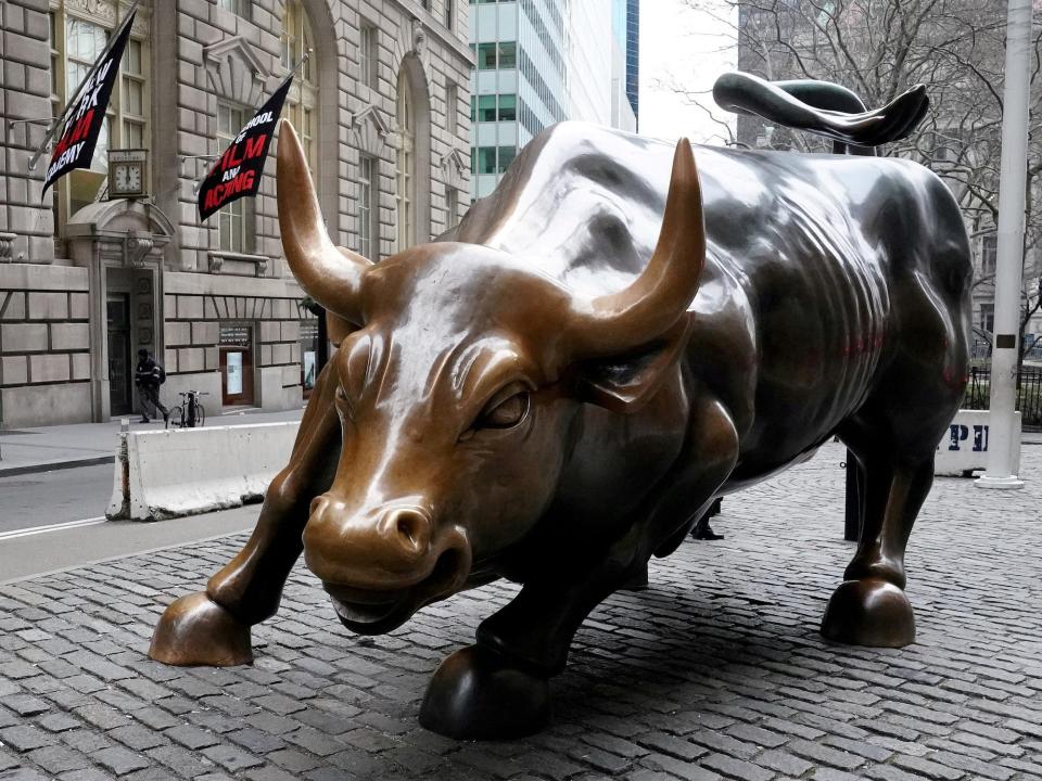 large bronze statue of bull in running stance in a brick plaza