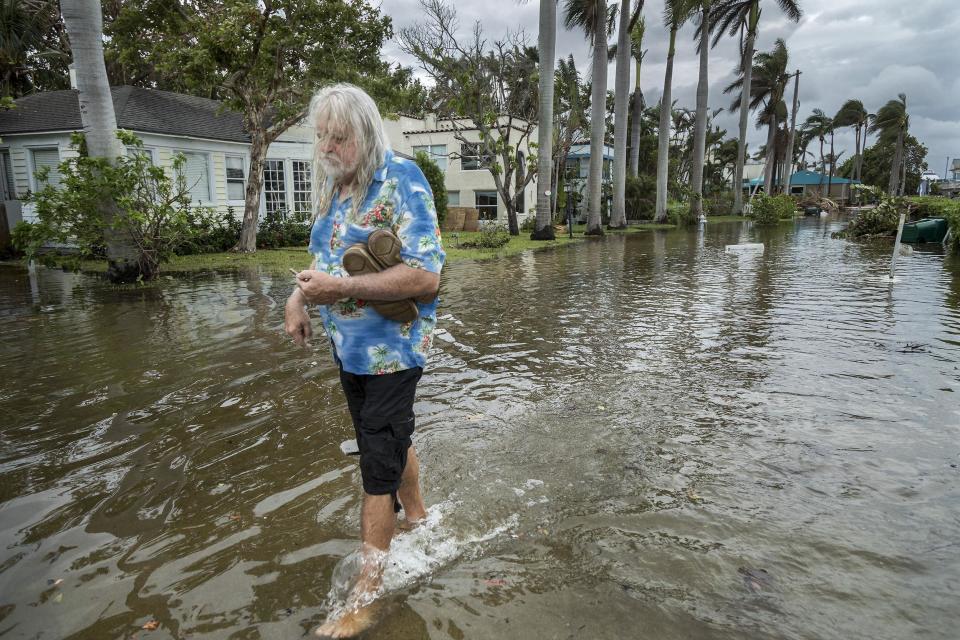 C.J. Johnson wades from his home on Marine Way after king tides flooded the street and brought water into his home in Delray Beach in October 2017. Scientists say such flooding will become more common as climate change raises the sea level.