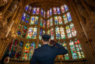 Flying Officer James Buckingham salutes The Battle of Britain memorial window inside Westminster Abbey, the stained glass window by Hugh Easton that contains the badges of the fighter squadrons that took part in the Battle.