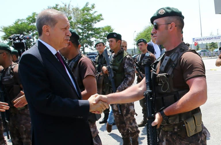 Turkish President Recep Tayyip Erdogan (L) shakes hands with a guard during his visit to the Police Special Operation Department headquarters in Ankara