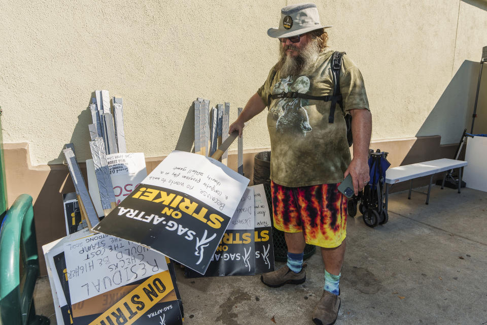 Actor Jack Black looks for a picket sign as joins demonstrators outside the Paramount Pictures Studio in Los Angeles, Tuesday, Sept. 26, 2023. (AP Photo/Damian Dovarganes)