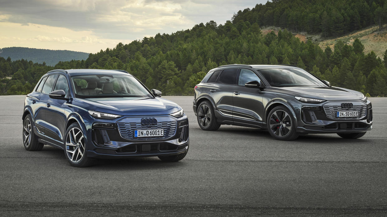  Two Audi Q6 e-tron cars in a car park in front of mountains. 