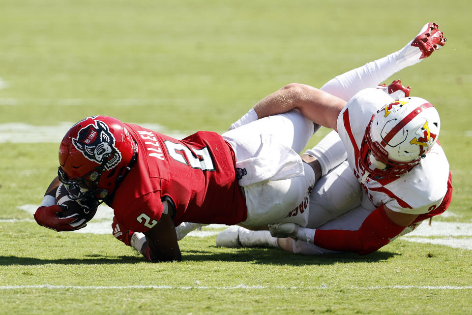 North Carolina State's Michael Allen (2) stretches for extra yards in the grasp of VMI's Evan Eller (2) during the first half of an NCAA college football game in Raleigh, N.C., Saturday, Sept. 16, 2023. (AP Photo/Karl B DeBlaker)