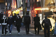 People wearing face masks to protect against the spread of the coronavirus walk on a street lined with bars and restaurants in Tokyo Wednesday, March 16, 2022. Japan’s Prime Minister Fumio Kishida on Wednesday announced plans to fully lift coronavirus restrictions on March 21 as new infections driven by the highly contagious omicron variant slow. (AP Photo/Koji Sasahara)