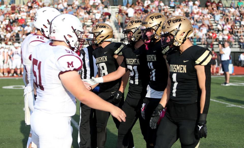 The captains of both teams greet each other for the coin toss during the Mishawaka vs. Penn football game Friday, Aug. 25, 2023, at Freed Field. The Kingsmen won over the Cavemen, 28-7.